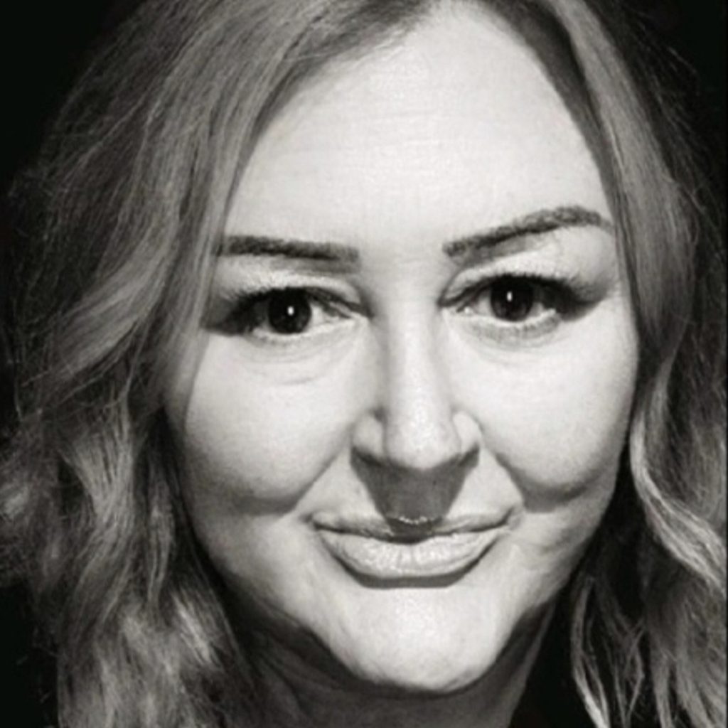A black and white photograph highlighting the texture and movement of long, wavy hair. The light-coloured waves cascade down against a dark background, creating a striking contrast. The monochrome palette emphasises the intricate details of the strands, focusing on their softness and flow.