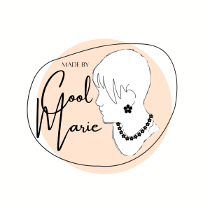 A stylised logo features the side profile of a person wearing a flower-shaped earring and a necklace made of star-shaped charms. The background is composed of overlapping peach-toned circular shapes. Elegant cursive text reads “MADE BY Cool Marie,” with “Cool” in large script and “Marie” slightly smaller, suggesting a personal, artistic brand—possibly focused on fashion, jewellery, or handmade creations.